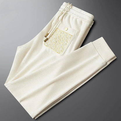 Full-length unisex travel & lounge pants in comfortable ribbed fabric, featuring elegant gold trim.