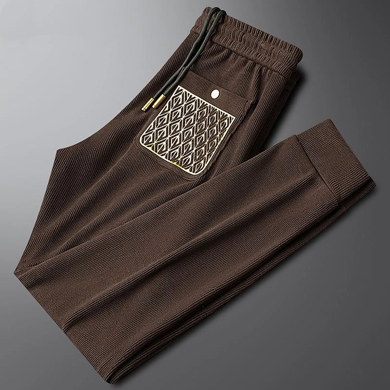 Unisex black comfort trousers, versatile for all, featuring ribbed texture & luxurious gold accents.