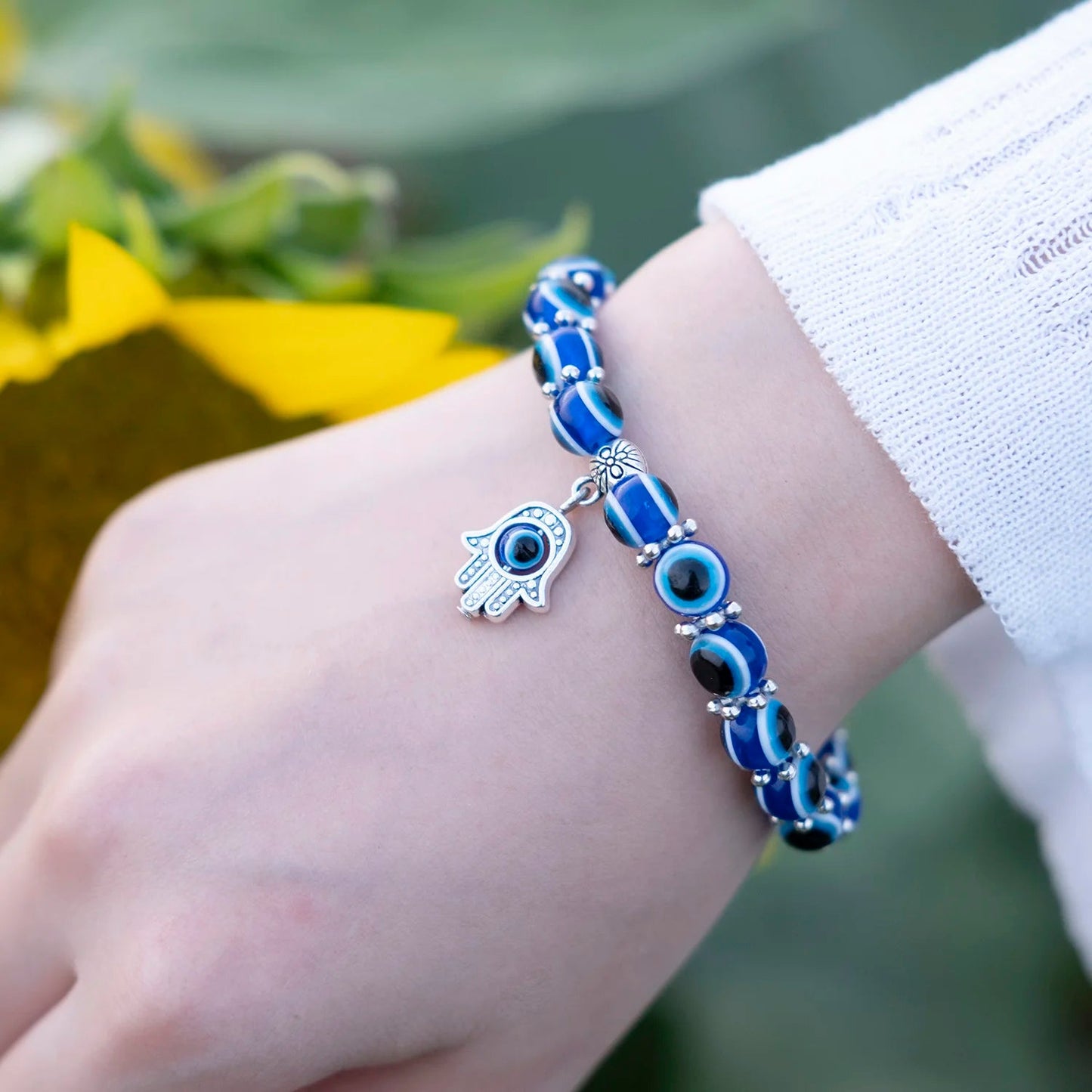 Unisex Evil Eye Anklet featuring a Hamsa hand charm for spiritual protection. Blue beaded stretch fit jewelry.