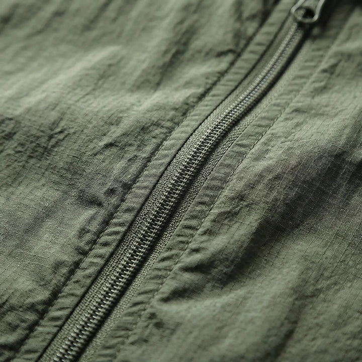 Hiker wearing a unisex hooded lightweight tactical windbreaker jacket in an outdoor setting. Quick-dry & water repellent.