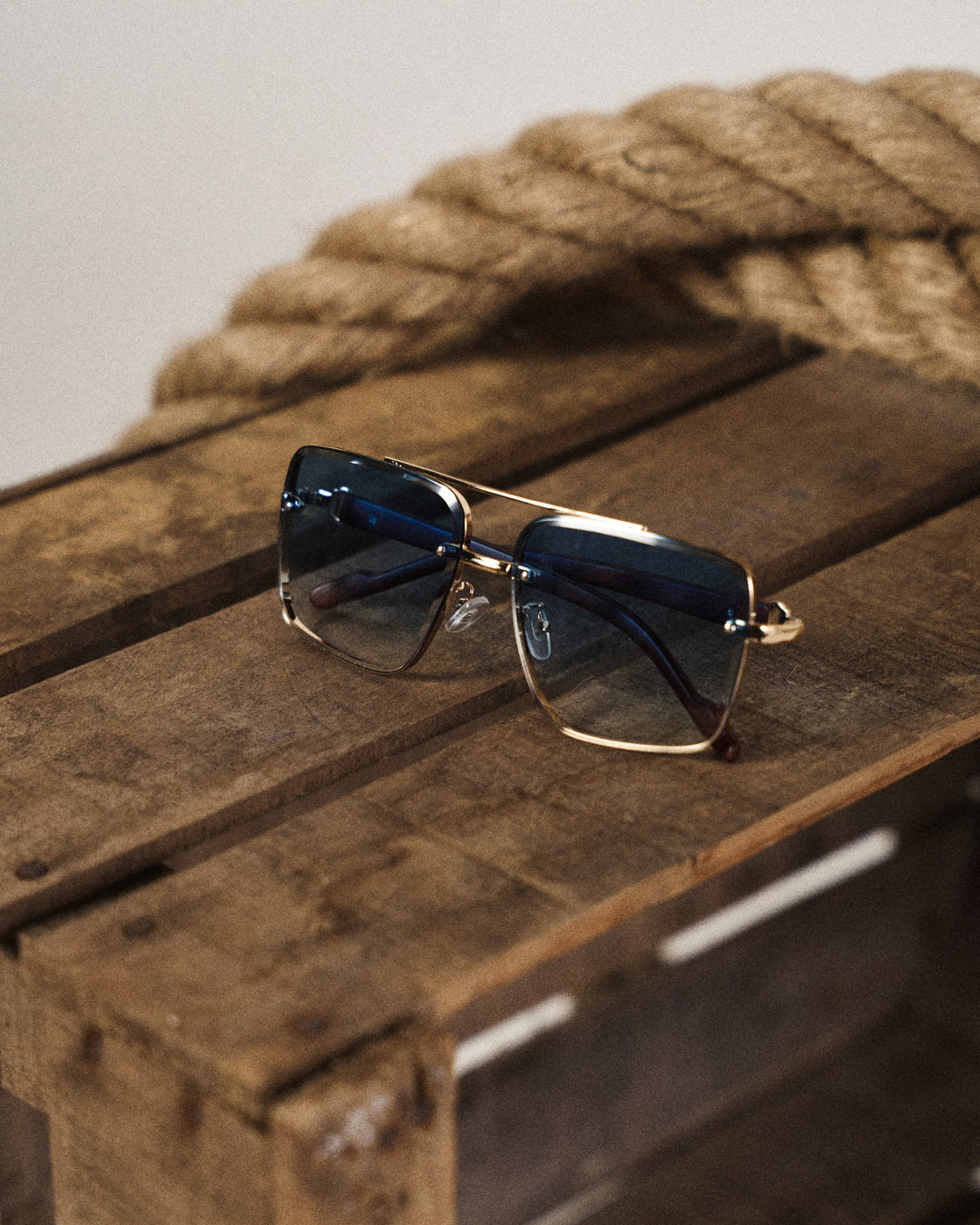 Close-up of square lens sunglasses, showcasing detail of wood arms and sophisticated metal frame.