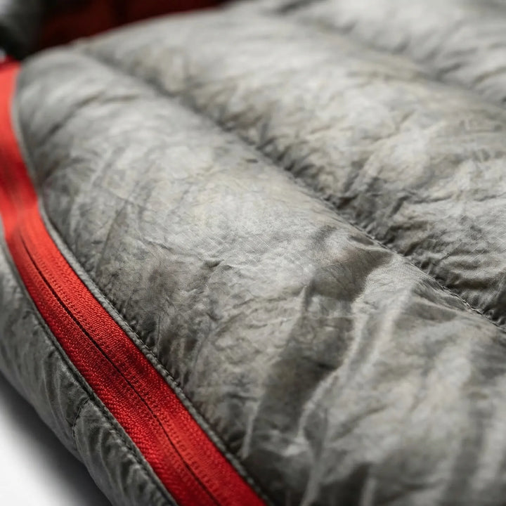 Person resting comfortably in a unisex ultralight down mummy sleeping bag for outdoor 3-season camping.