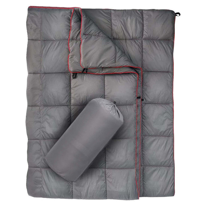 Person enjoying the warmth of their insulated camping poncho by a lake.
