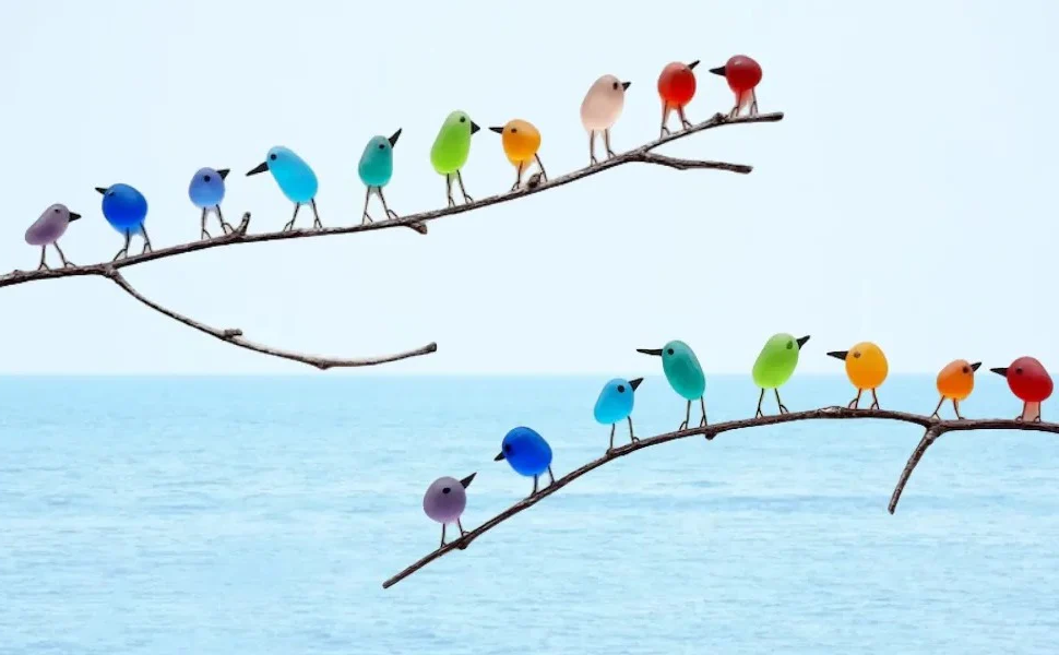 Sustainable sea glass bird art, featuring a delicate rainbow design on driftwood, ideal for nature-lovers.