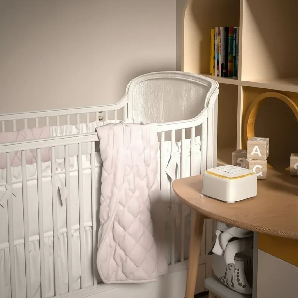 Compact white noise sleep aid on a nightstand, enhancing restful sleep & relaxation in a bedroom.