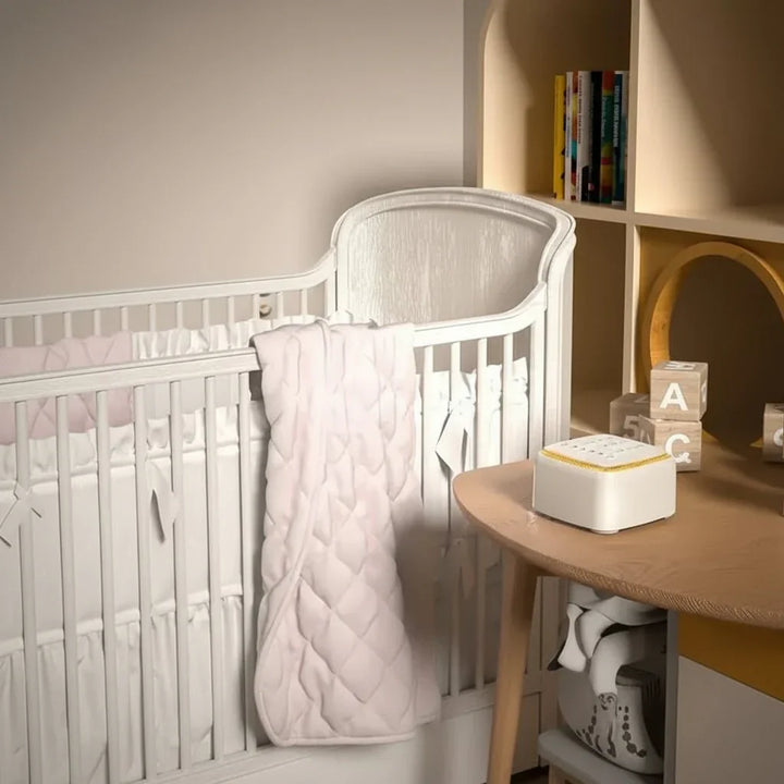 Compact white noise sleep aid on a nightstand, enhancing restful sleep & relaxation in a bedroom.