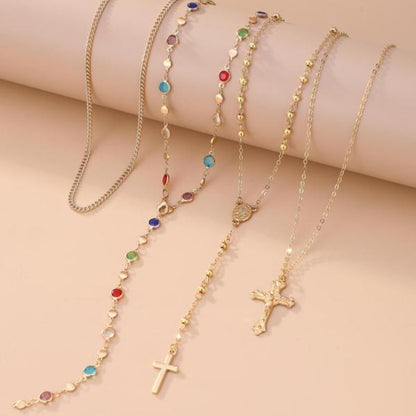 Spiritual women's 4-piece layered cross necklace set with crystal details. Elegant gold & silver religious jewelry.