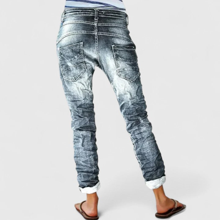 Close-up of women's acid wash denim skinny jeans, showcasing the button fly closure & detailed contrast stitching.