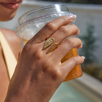 Close-up of a guardian angel wings feather ring for women. Gold-plated, adjustable & made from stainless steel.