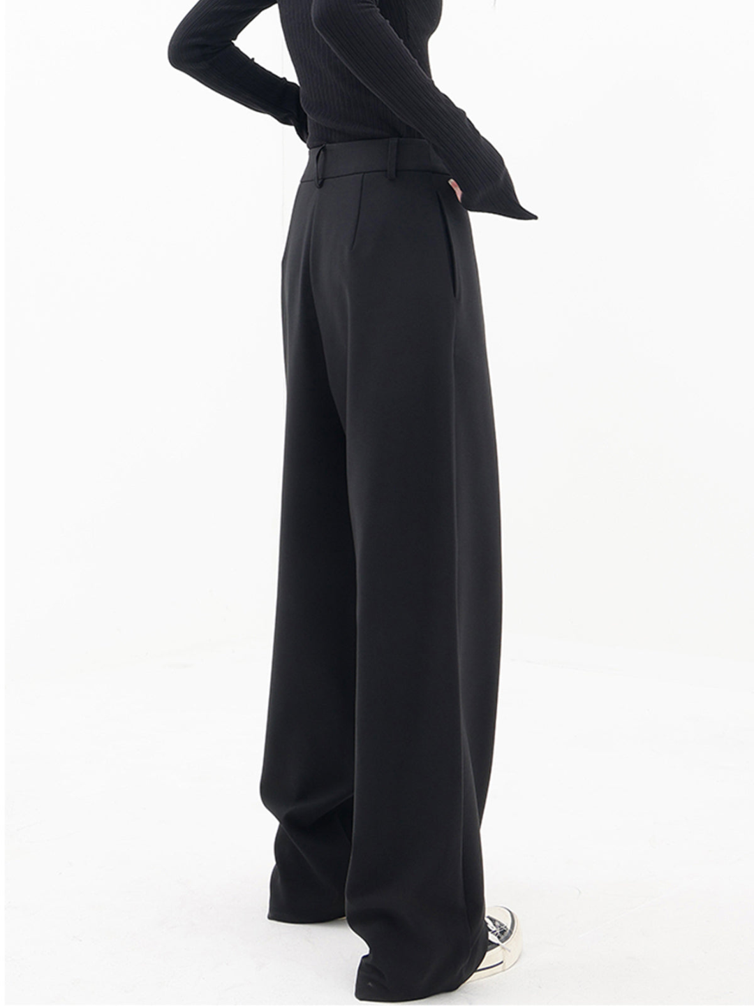 Back view of women's baggy trousers, highlighting the relaxed wide leg, comfortable fit, and modern asymmetric waist.