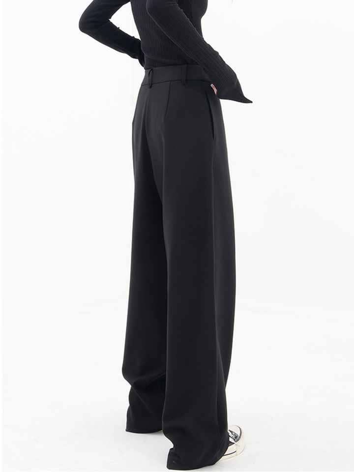 Back view of women's baggy trousers, highlighting the relaxed wide leg, comfortable fit, and modern asymmetric waist.