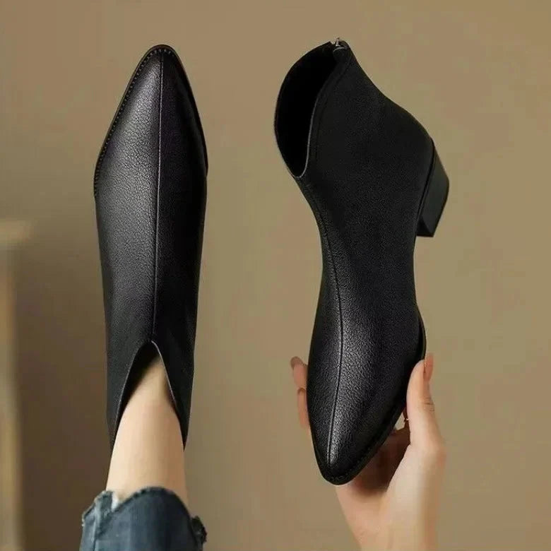 Woman wearing chic pointed-toe ankle boots with low heel, suitable for work or casual outings.