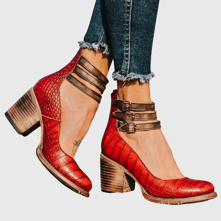 Stylish women's footwear: black ankle boots with a unique cutout design, buckle straps, and a block heel.