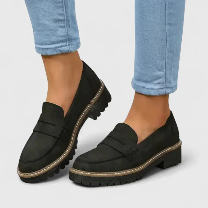 Women's black chunky lug-sole penny loafers for modern casual or dressy styles. Comfortable slip-on design.