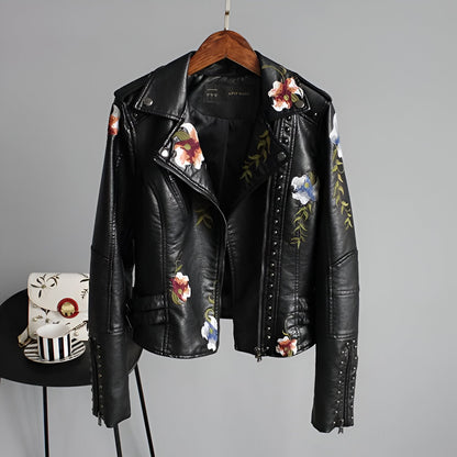 Women's black studded biker jacket with colorful floral embroidery, edgy moto style, and asymmetrical zipper.