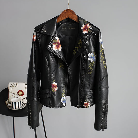 Women's black studded biker jacket with colorful floral embroidery, edgy moto style, and asymmetrical zipper.
