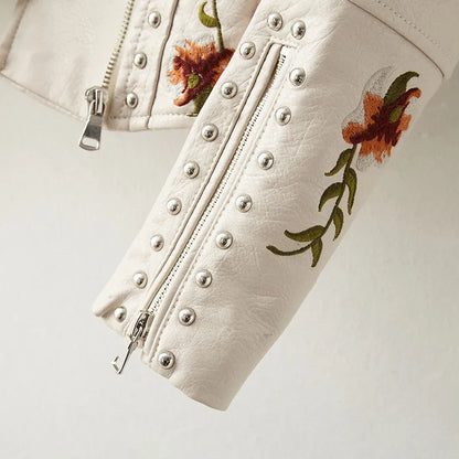 Detailed women's studded moto jacket featuring intricate floral stitching and a classic asymmetrical zip.