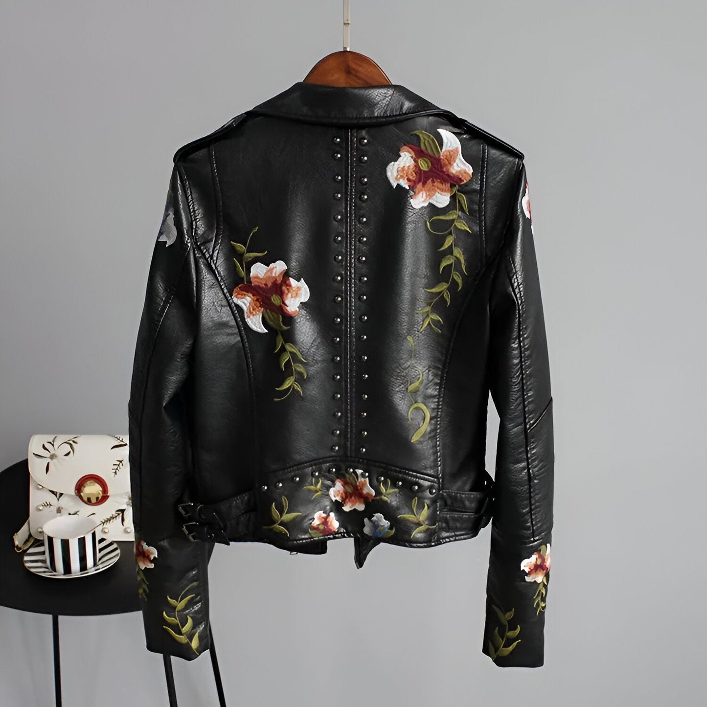 Stylish women's studded moto jacket featuring intricate floral embroidery on the back, perfect for edgy fashion.
