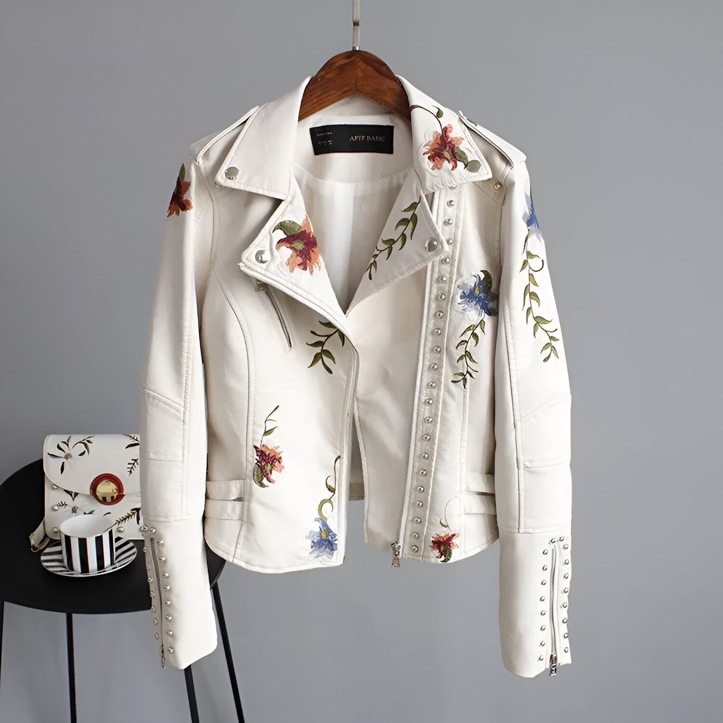 Front view of a women's edgy studded biker jacket with an asymmetrical zipper and subtle floral accents.