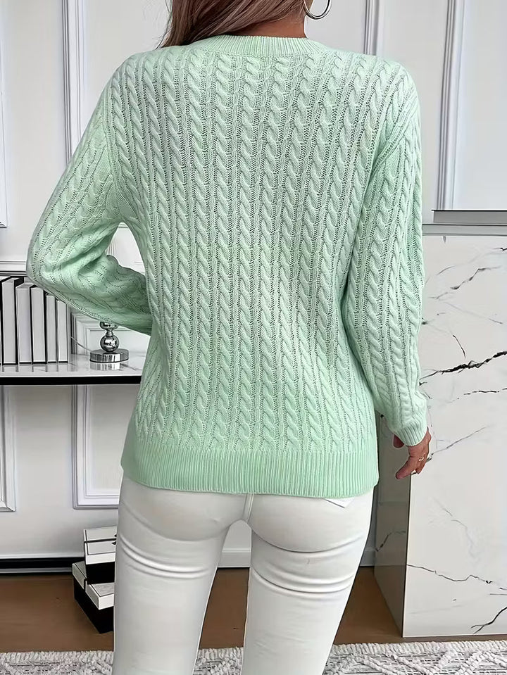 Close-up of intricate cable knit pattern on a women's cozy crew neck sweater, perfect for autumn.