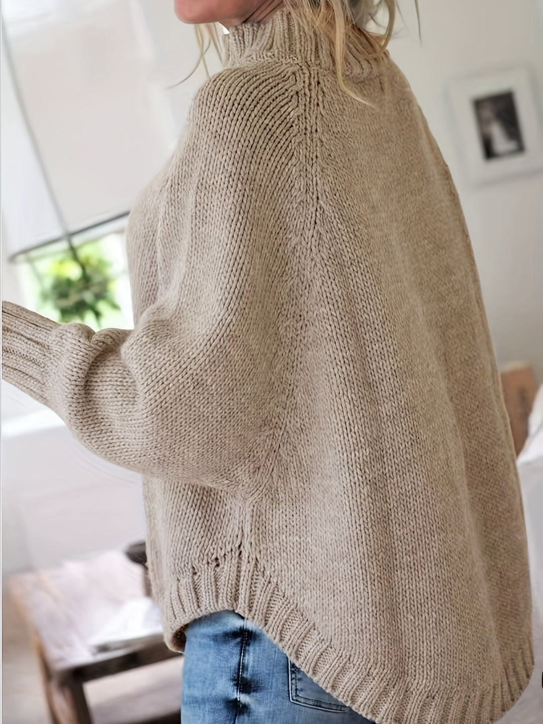 Stylish women's high-neck cable knit sweater, featuring an oversized fit and elegant flared hem for comfort.