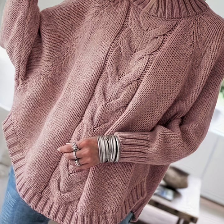 Women's cable knit sweater: high neck, batwing sleeves, and flared hem. Cozy oversized fit for fall/winter.