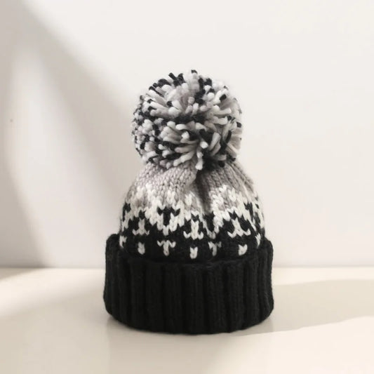Women's cozy knit beanie with snowflake pattern & faux fur pompom, perfect for winter fashion.