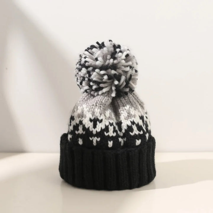 Women's cozy knit beanie with snowflake pattern & faux fur pompom, perfect for winter fashion.