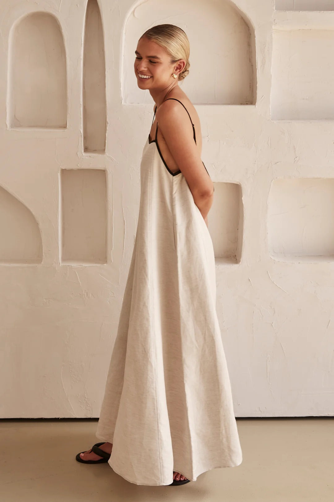 Detail shot of a women's square neck cream maxi dress. Focus on contrast trim, spaghetti straps & comfortable summer fabric.
