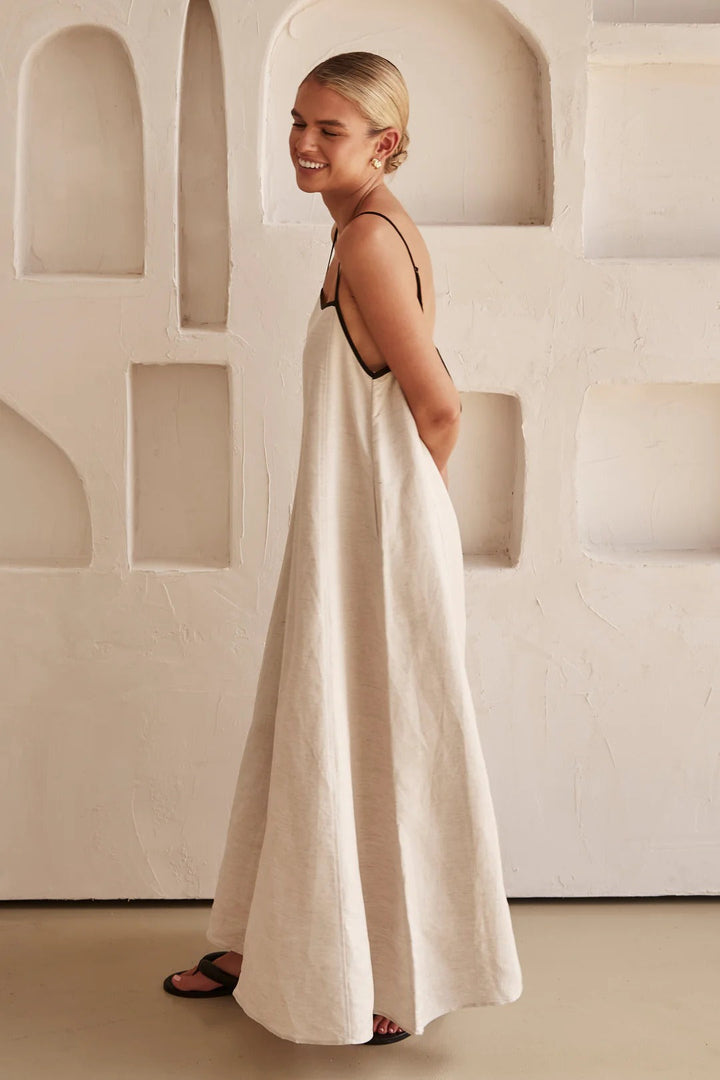 Detail shot of a women's square neck cream maxi dress. Focus on contrast trim, spaghetti straps & comfortable summer fabric.