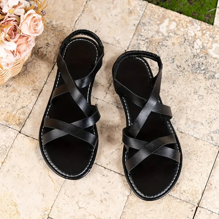 White criss-cross strap roman flat sandals for women, offering a fashionable and comfortable fit.