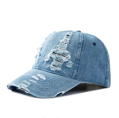 Close-up of a women's distressed denim hat, showing ripped details & faded texture for streetwear.