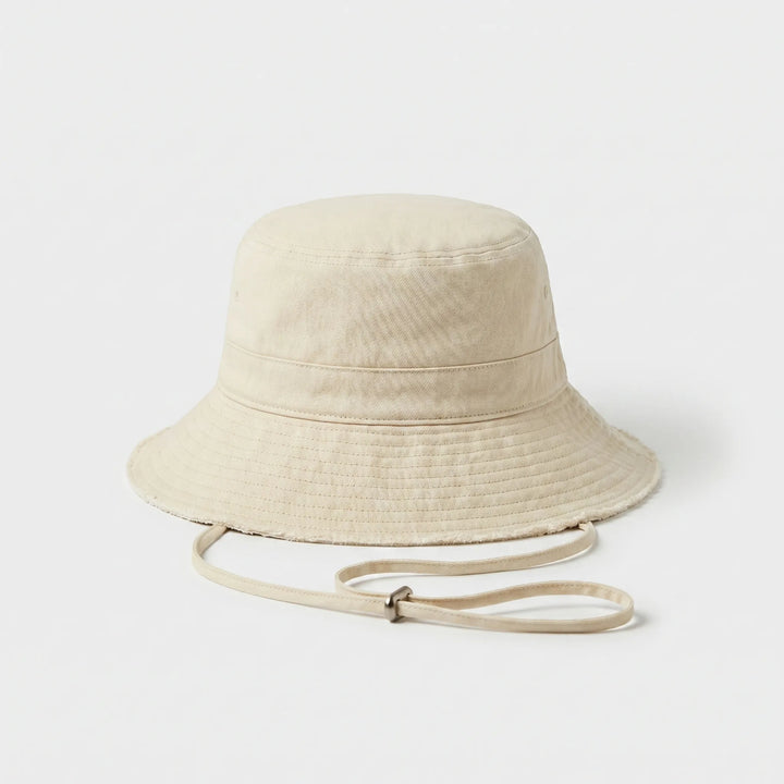 Casual women's summer bucket hat, distressed fabric, wide brim, and secure chin strap for sun protection.