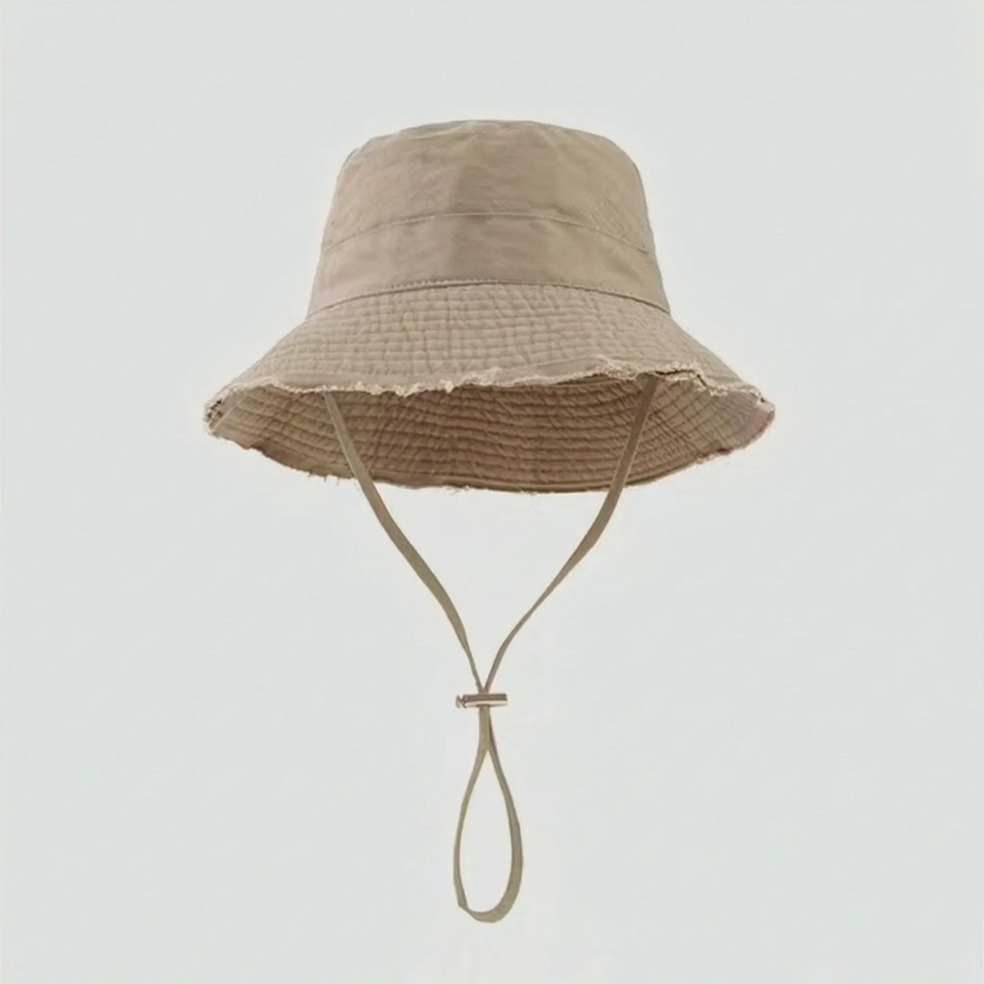 Relaxed women's distressed bucket hat with a secure chin strap, offering sun protection & casual style.