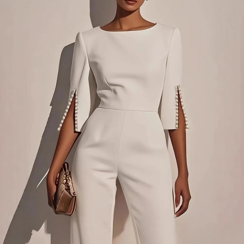 Close-up of elegant women's tailored jumpsuit showing exquisite pearl cuffs and sleek fabric detail.
