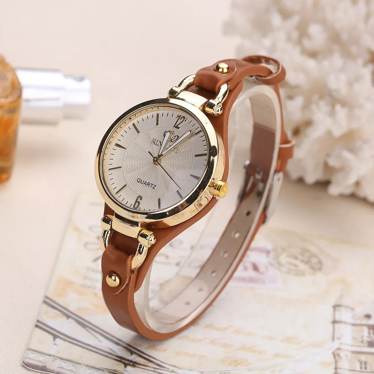 Women's elegant gold quartz watch with a sleek black vegan leather strap.