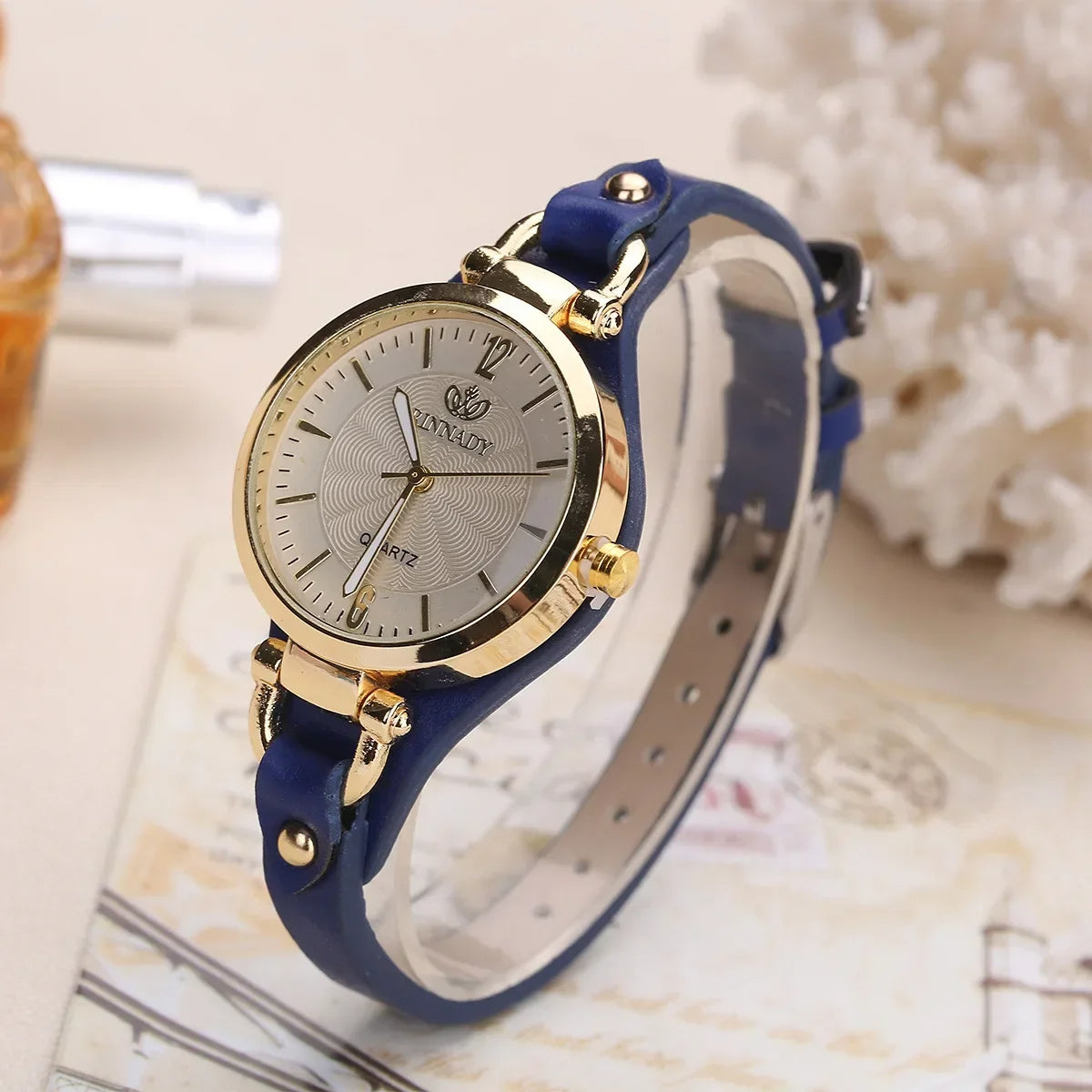 Minimalist women's fashion watch, gold case, white dial, and stylish brown vegan leather band.