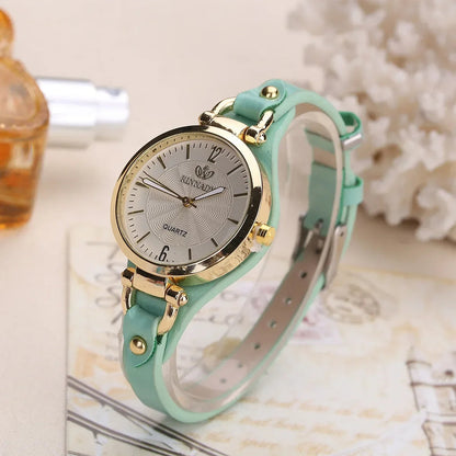 Close-up of elegant women's gold quartz watch, displaying its minimalist dial and soft vegan leather band.