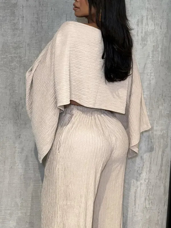 Fashionable women's coordinated two-piece set: one-shoulder pleated top and flowy wide-leg trousers for resort.