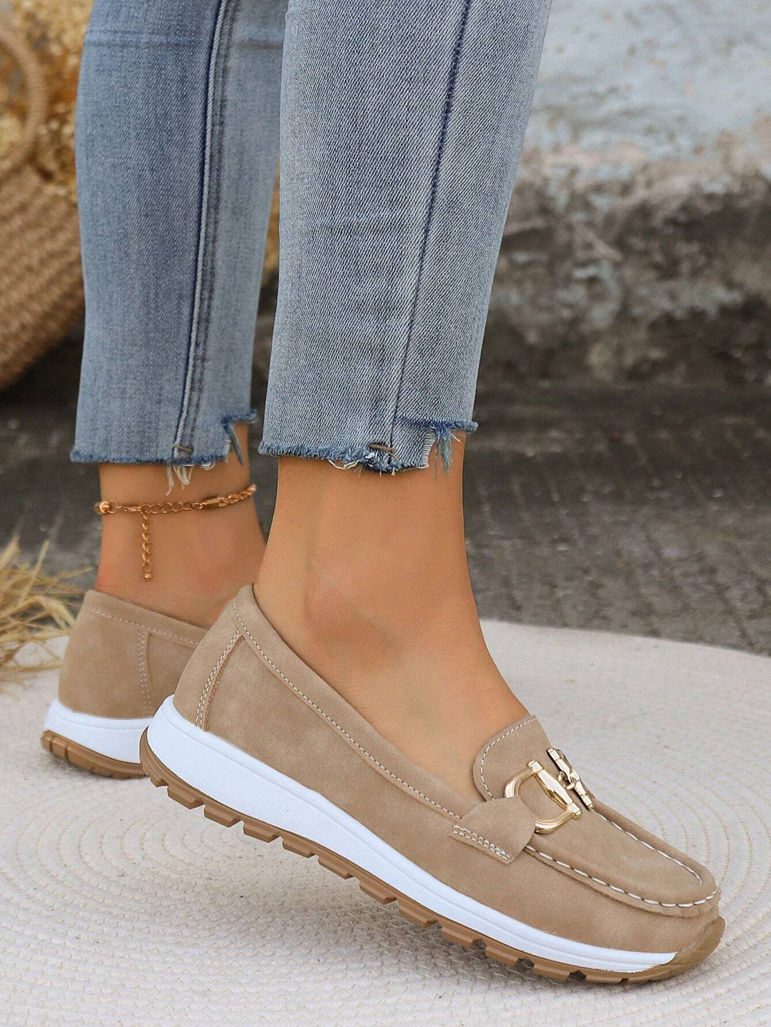 Close-up of a women's flat loafer showcasing the elegant gold buckle and soft, slip-on design.