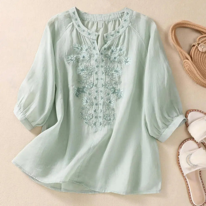 Women's comfortable white blouse featuring colorful floral embroidery, an elegant top for casual wear.