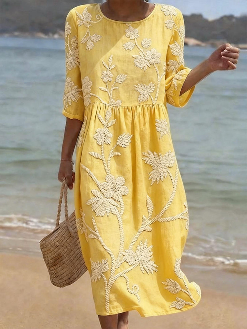 Close-up of women's floral embroidered midi dress with three-quarter sleeves, showcasing intricate stitching.