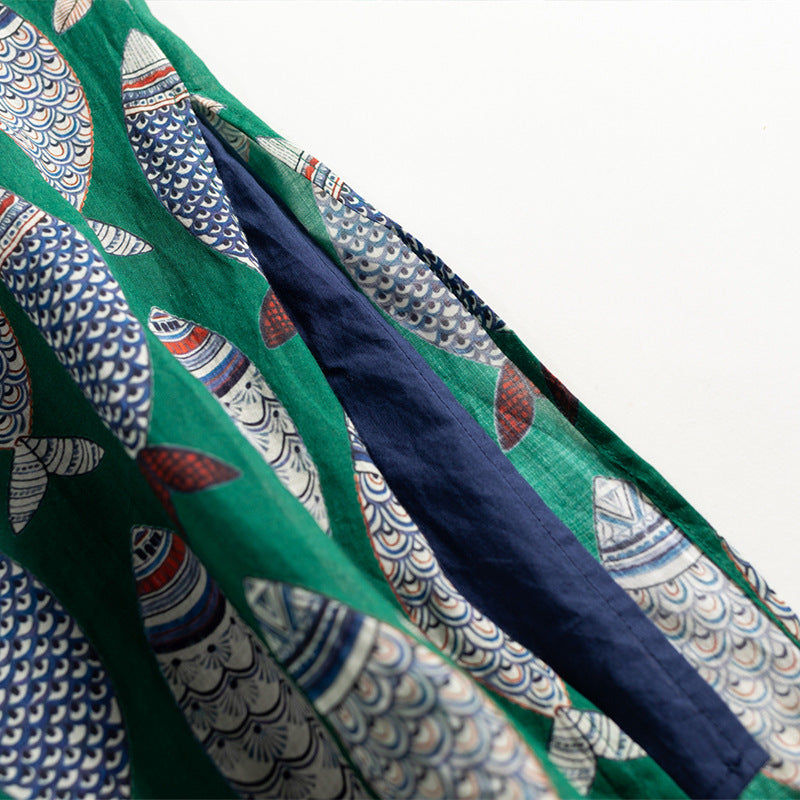 Close-up of a women's flowy sleeveless maxi dress with a vibrant, playful fish print design.