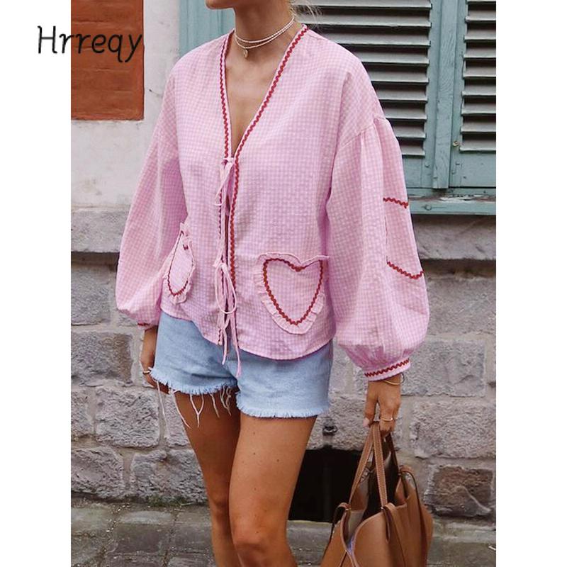 Chic women's gingham blouse featuring heart appliques, a tie-front design, and elegant voluminous sleeves. Ideal for summer.
