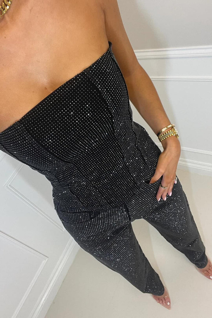 Close-up: Shimmering women's glitter crop top fabric, sparkling. Part of high-waist jeans party outfit set.