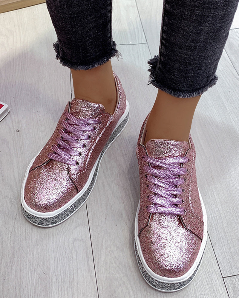 Close-up of women's glitter platform sneakers, highlighting the shimmering fabric & sturdy sole.
