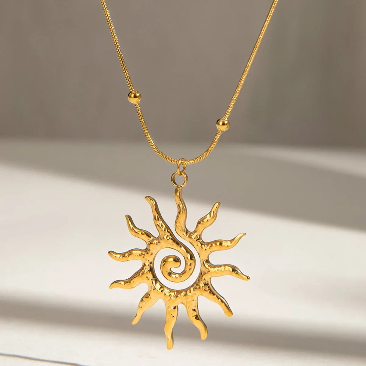 Elegant women's sun charm necklace in gold-plated stainless steel, a chic bohemian jewelry accessory.
