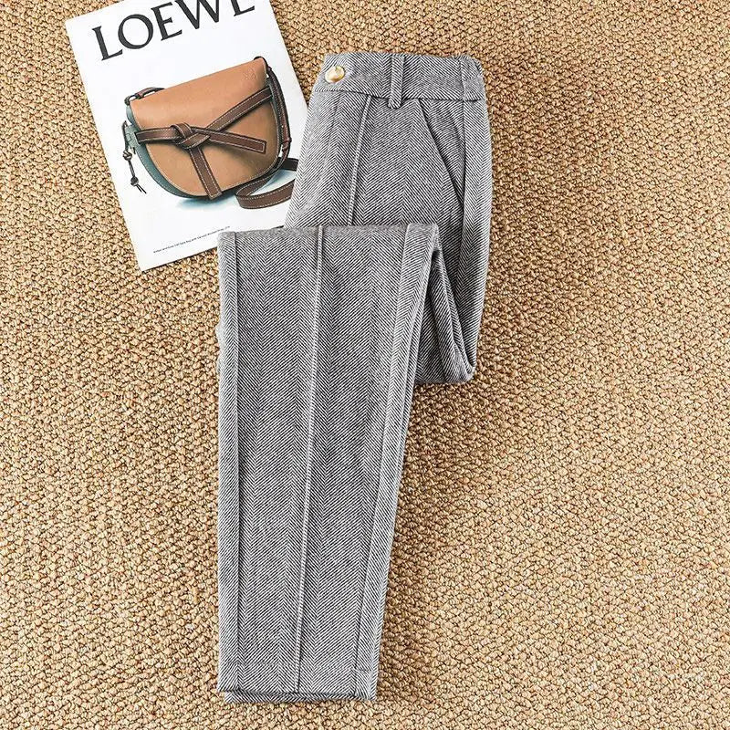 Stylish women's high-waisted herringbone trousers paired with a blouse, ideal for professional look.