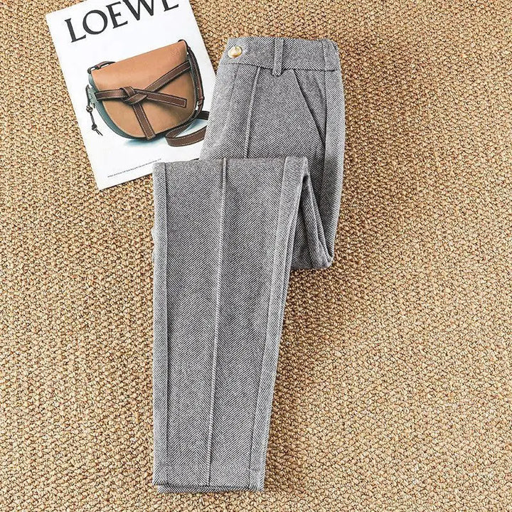Stylish women's high-waisted herringbone trousers paired with a blouse, ideal for professional look.
