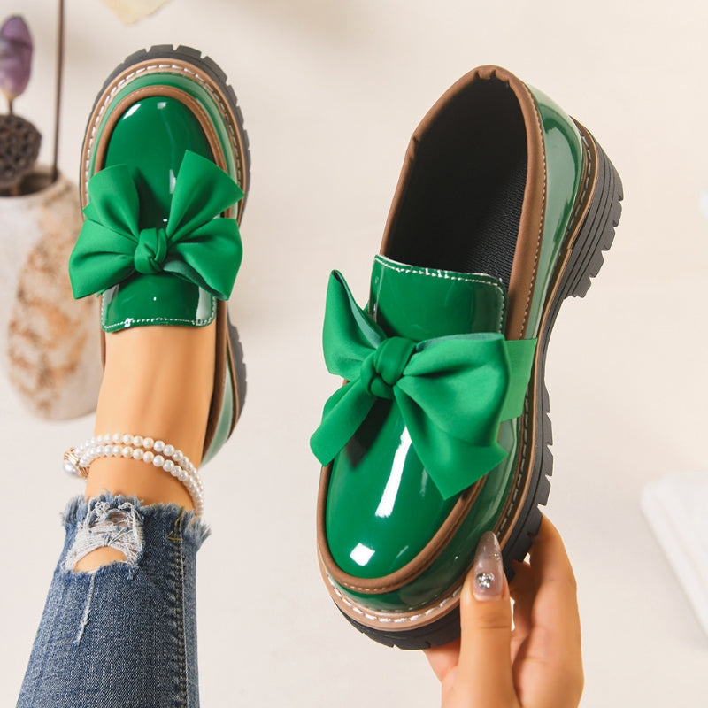Close-up of Lucente women's loafer showcasing chic bowknot accent on shiny black patent slip-on platform shoe.